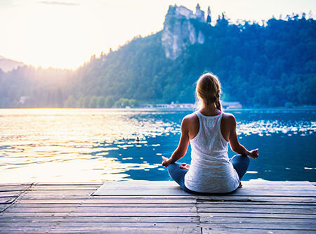 Frau im Meditationssitz mit Ausblick auf einen See