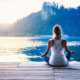 Frau im Meditationssitz mit Ausblick auf einen See