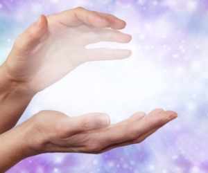 Hands cupped around light on a background of blues and purples.