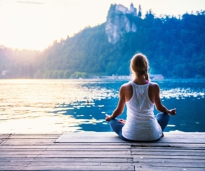 Frau meditiert am See - Yogalehrerausbildung