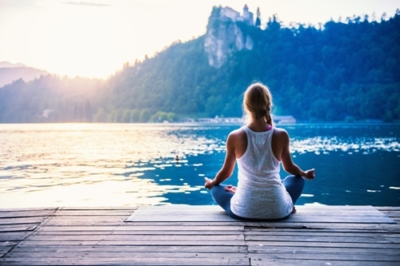 Frau meditiert am See - Yogalehrerausbildung